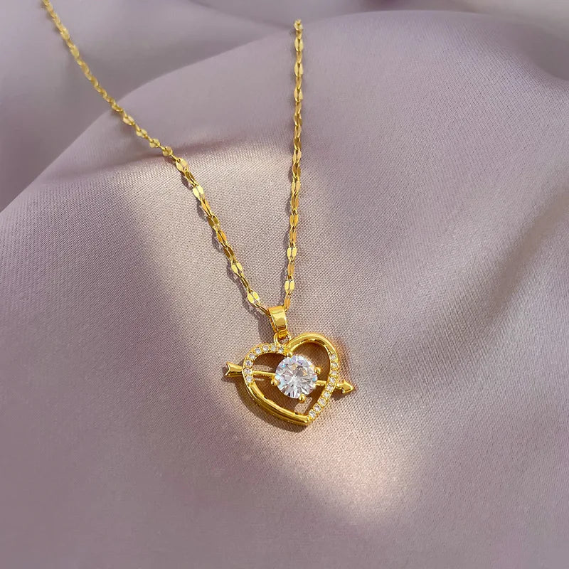 Gold necklace with a heart-shaped pendant featuring a diamond on a soft pink fabric background