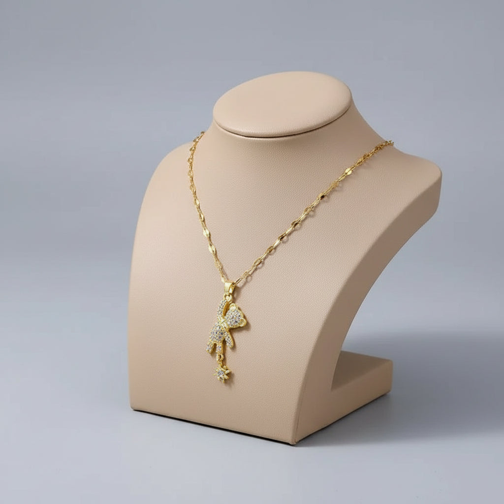 Gold teddy bear pendant necklace on a beige box