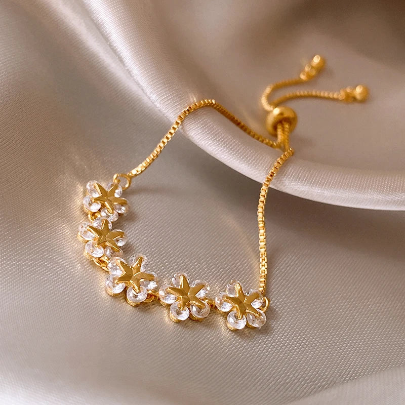 Gold bracelet with floral designs on a beige fabric background