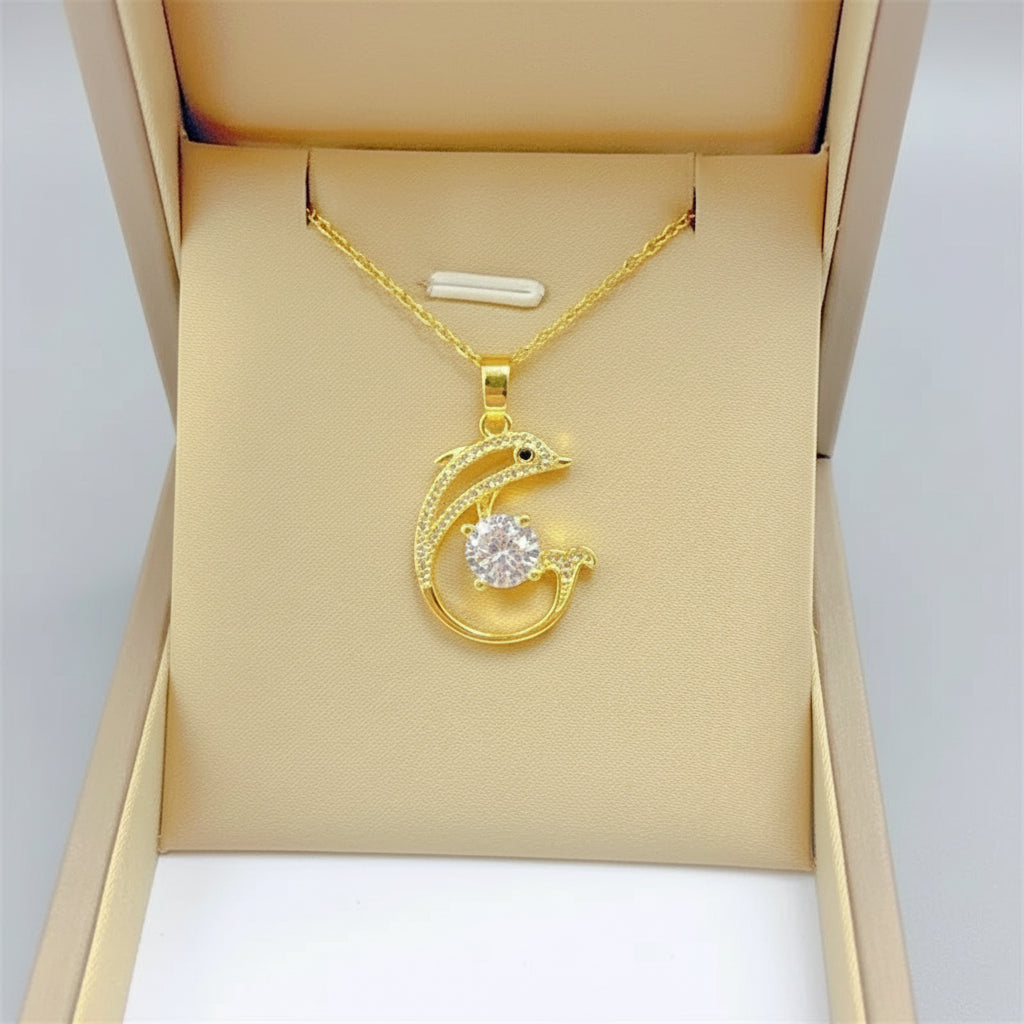 Gold necklace with a dolphin pendant in an open jewelry box on a white background