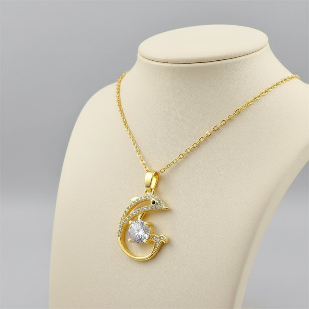 Gold necklace with a dolphin pendant on a beige background