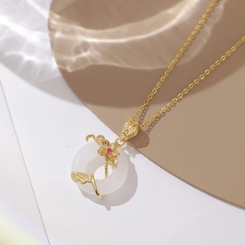 Gold necklace with a white pendant on a beige and white background