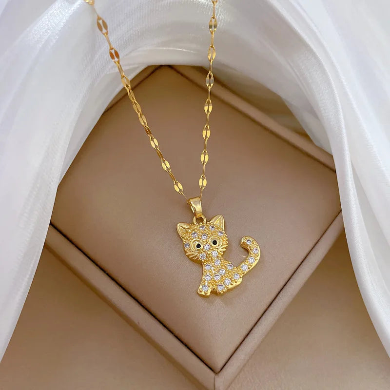 Gold cat-shaped pendant necklace on a beige stand with white fabric background