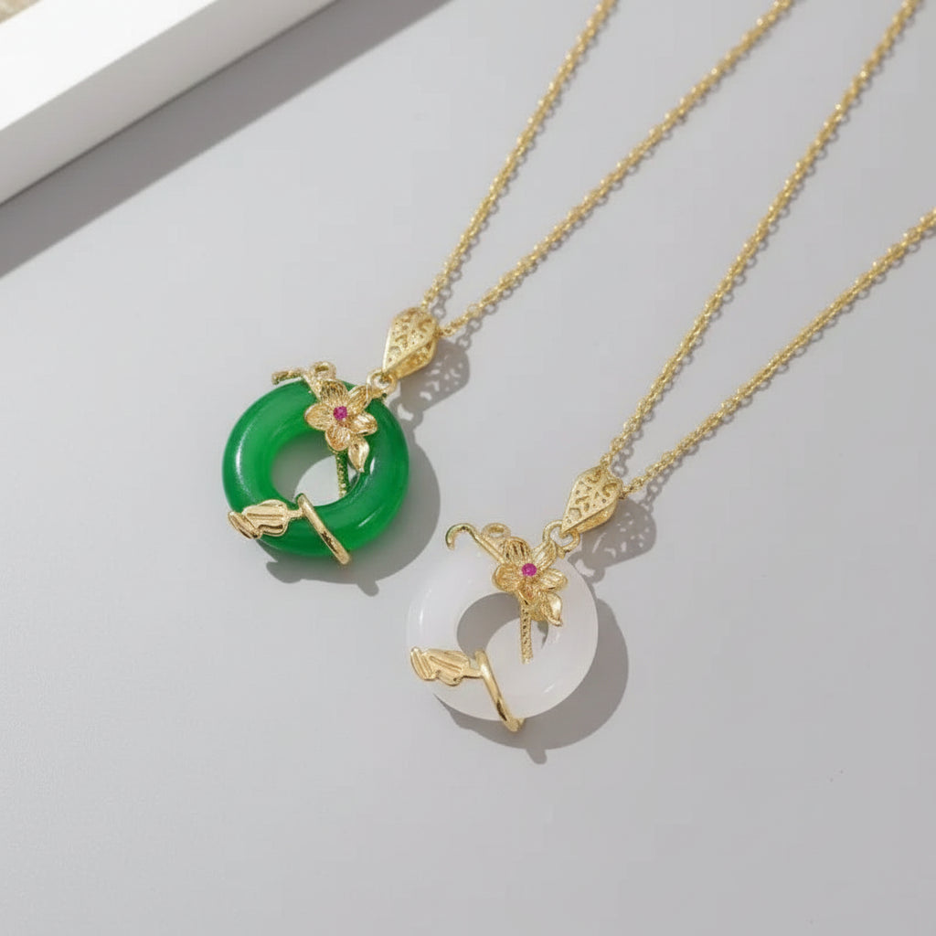 Gold necklaces with green and white pendants on a beige and white background