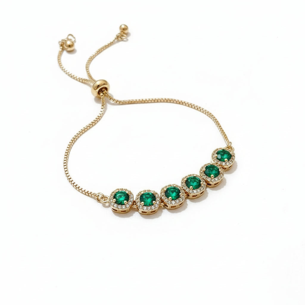 Gold bracelet with green gemstones on a white background
