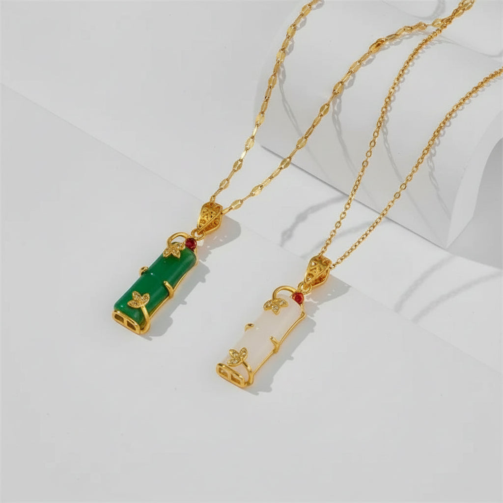 Two gold necklaces with green and white pendants on a white background